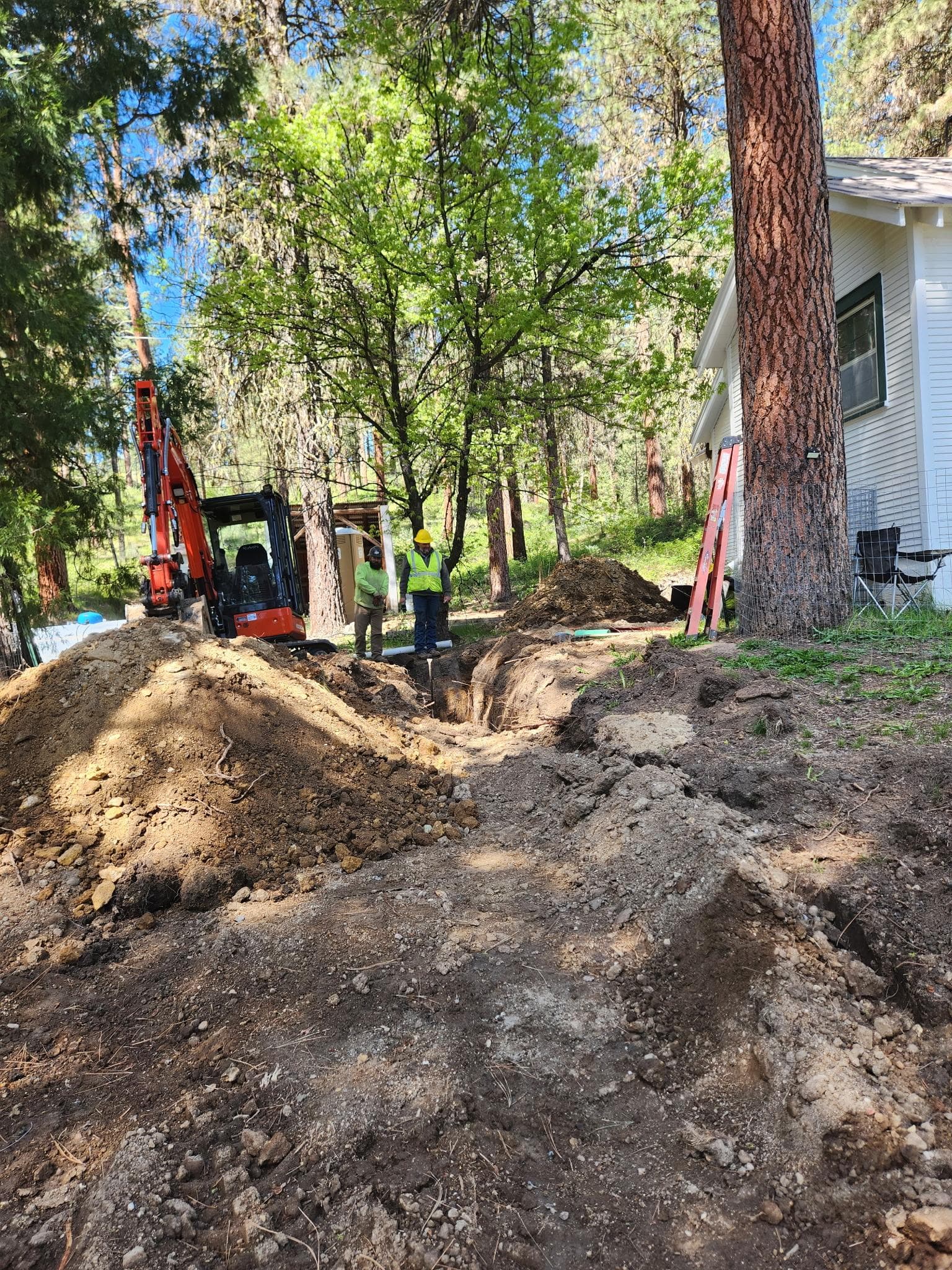 Residential excavation trench near a home during underground repair work.